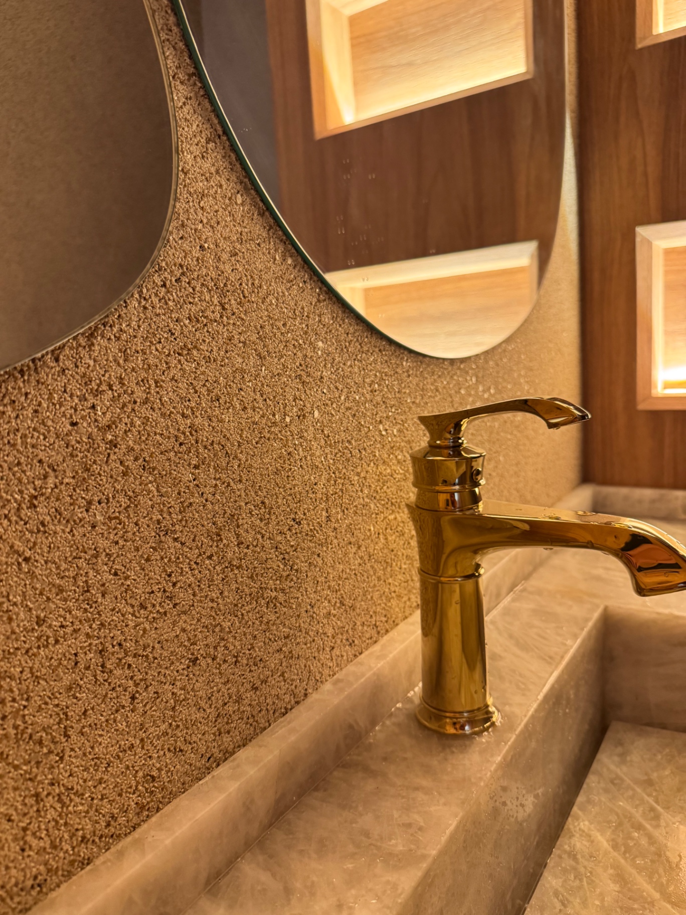 Lavabo com parede revestida em pedras naturais e iluminação decorativa
