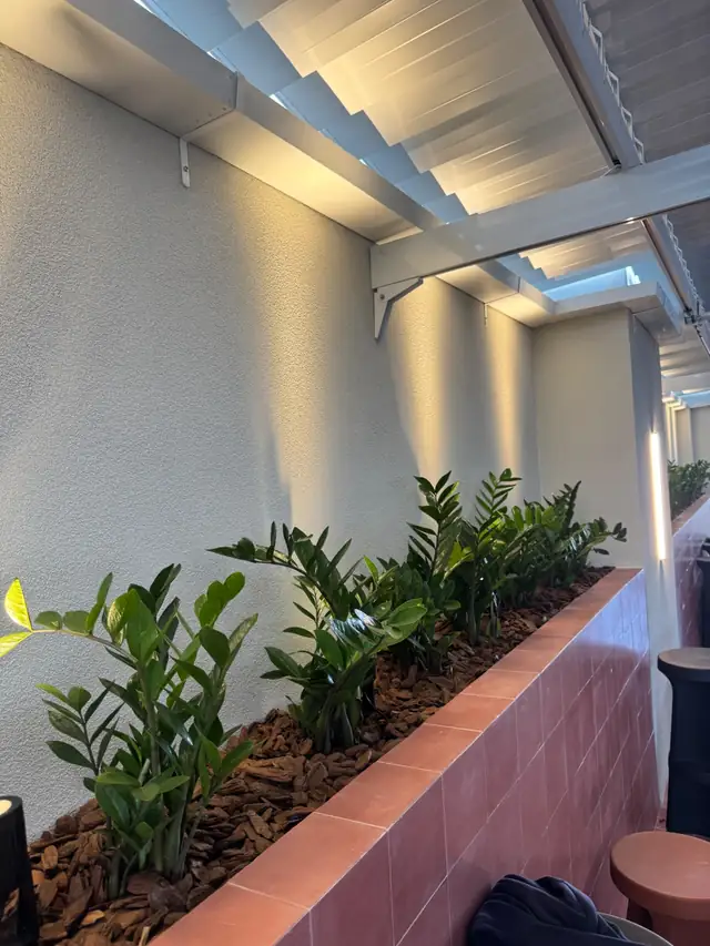 Área externa com floreira e parede em textura Granfino Cristaline iluminada