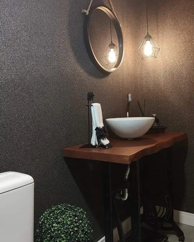 Lavabo com parede em pedras naturais escuras, cuba de apoio e bancada de madeira