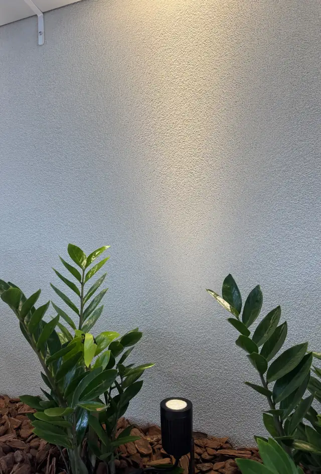 Parede de jardim com textura Granfino clara iluminada por espeto de jardim