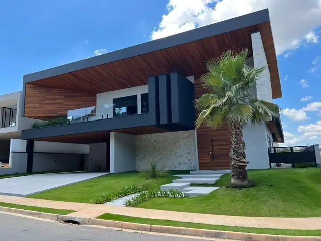 Residência contemporânea com volumes revestidos em pedras naturais e madeira
